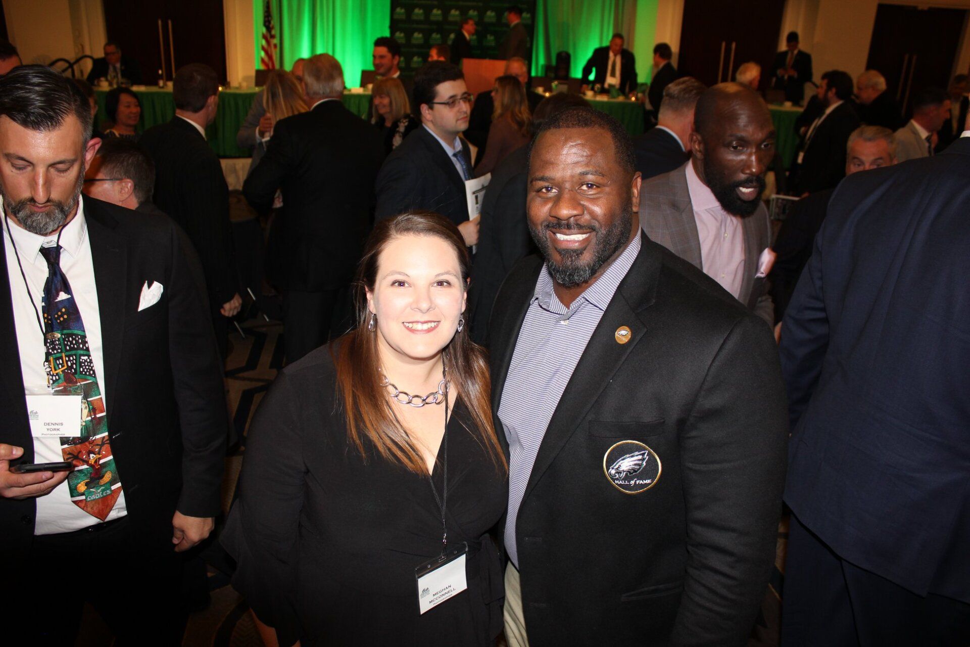 A man and a woman are posing for a picture in a crowded room.