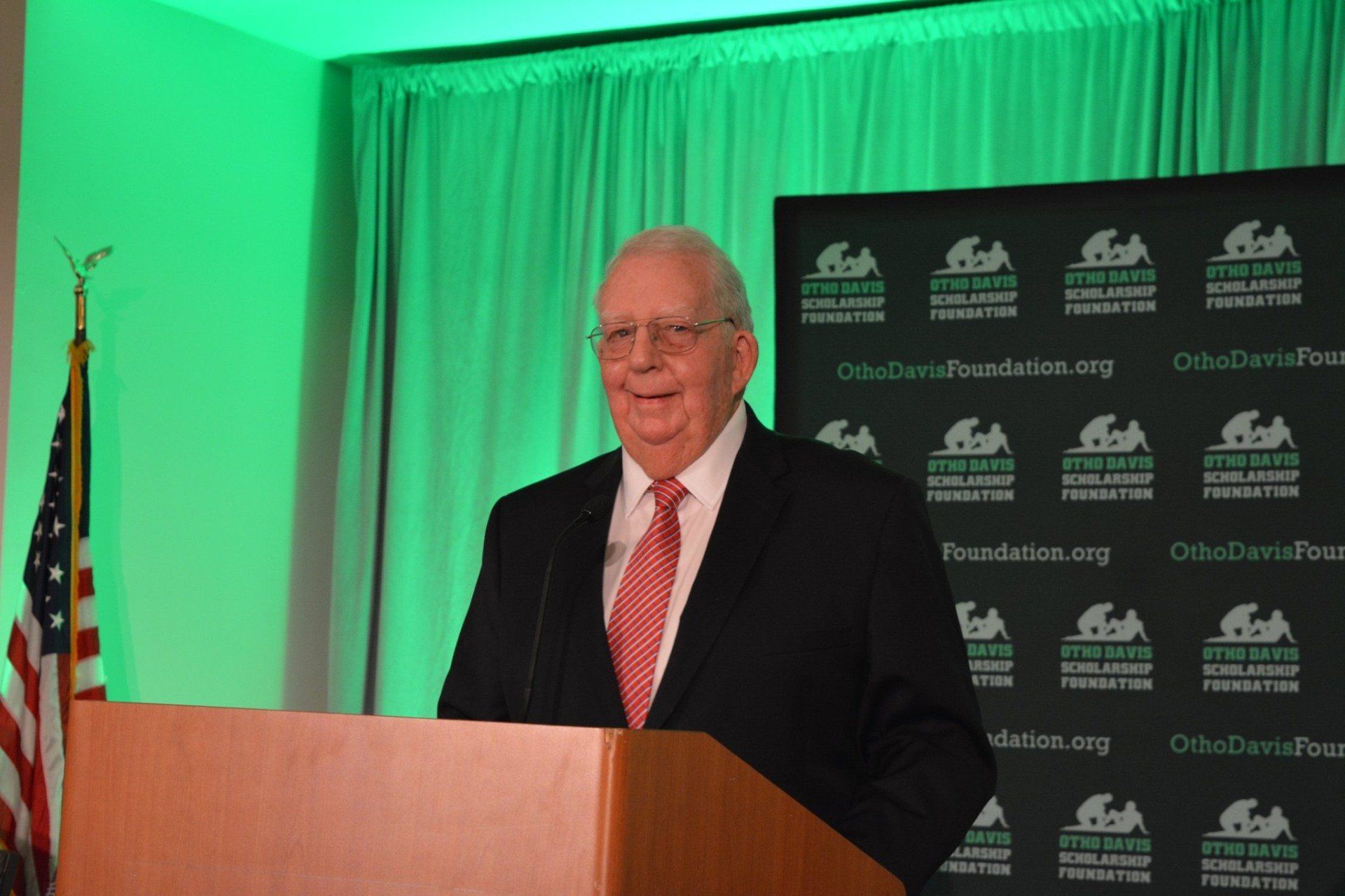 A man in a suit and tie is standing at a podium giving a speech.