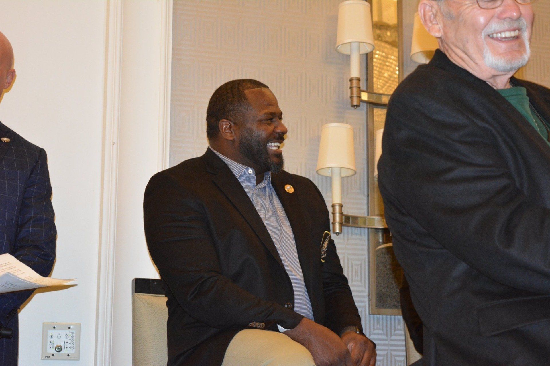A group of men are sitting in chairs and smiling.