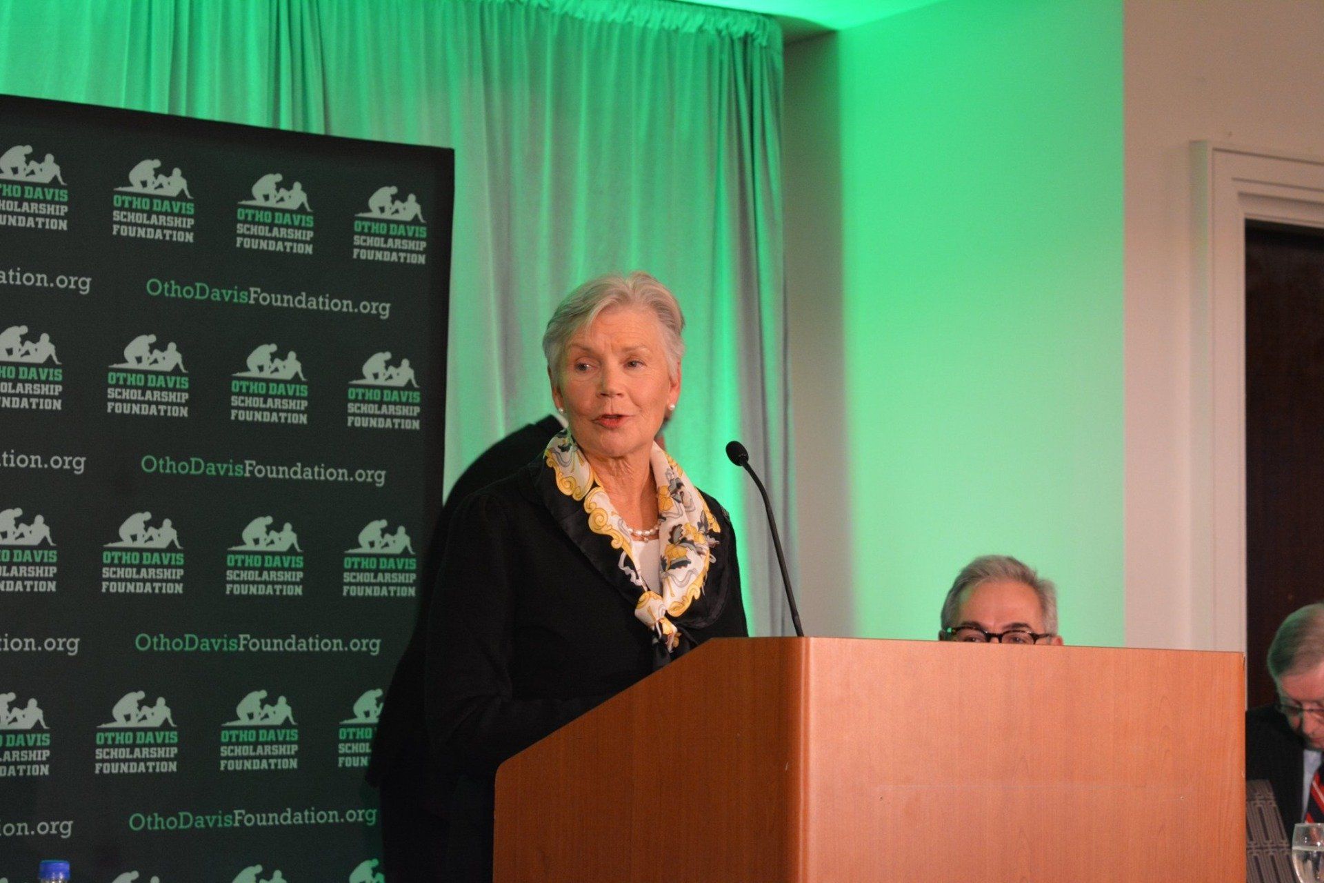 A woman is standing at a podium speaking into a microphone.