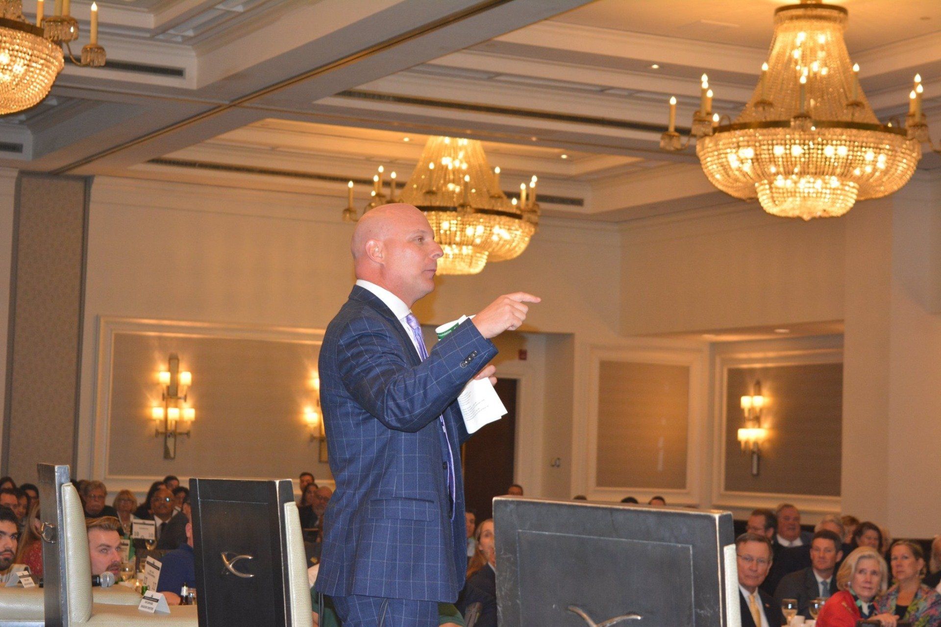 A man in a suit and tie is giving a speech in front of a crowd.
