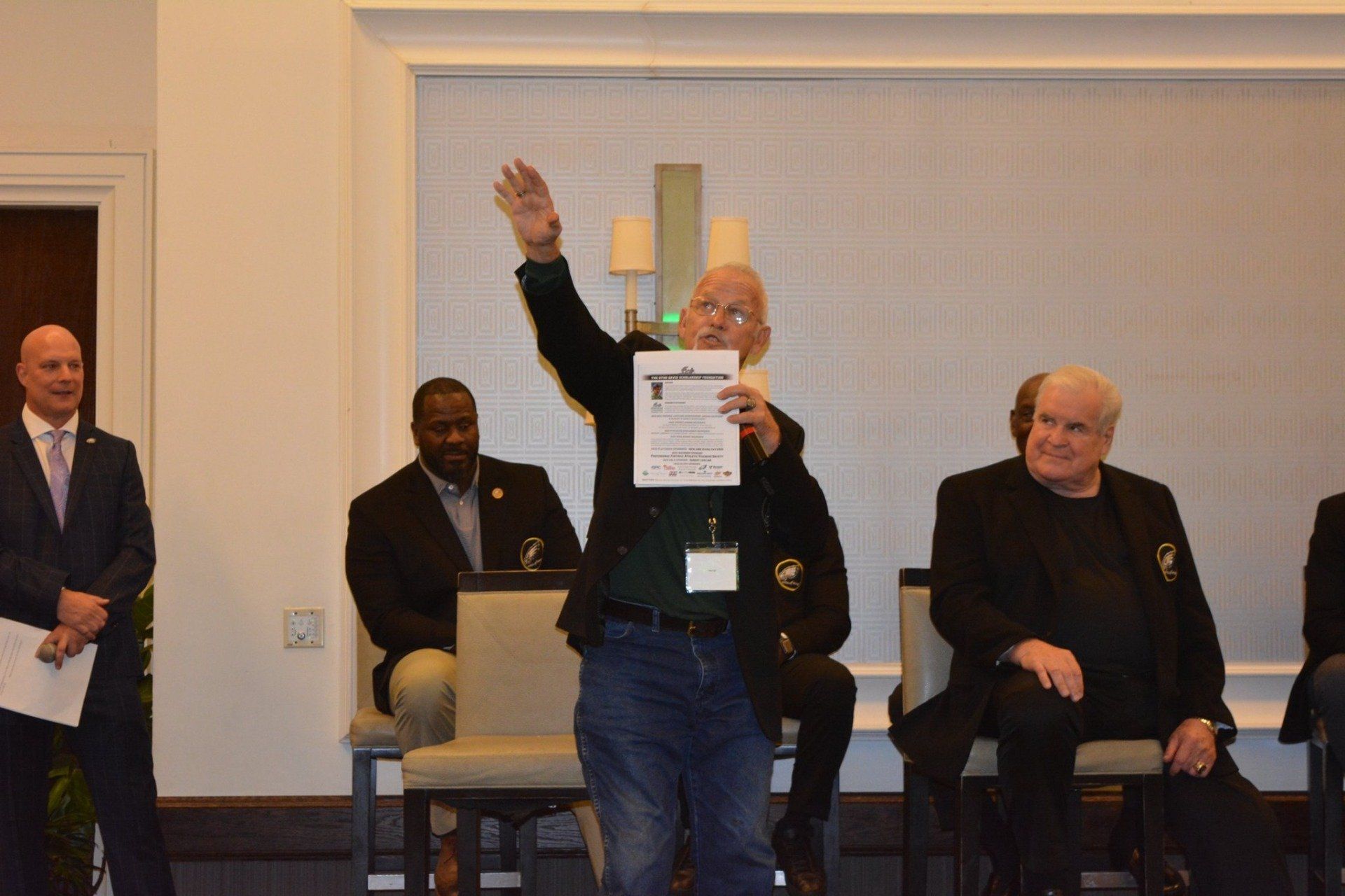 A man is holding a piece of paper in front of a group of men.