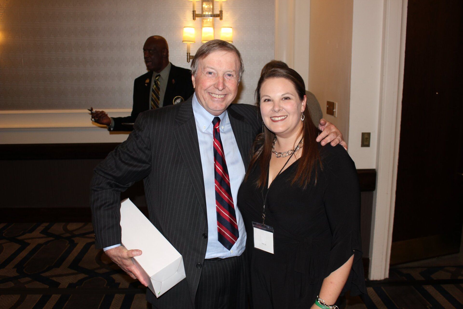 A man in a suit and tie poses with a woman in a black dress