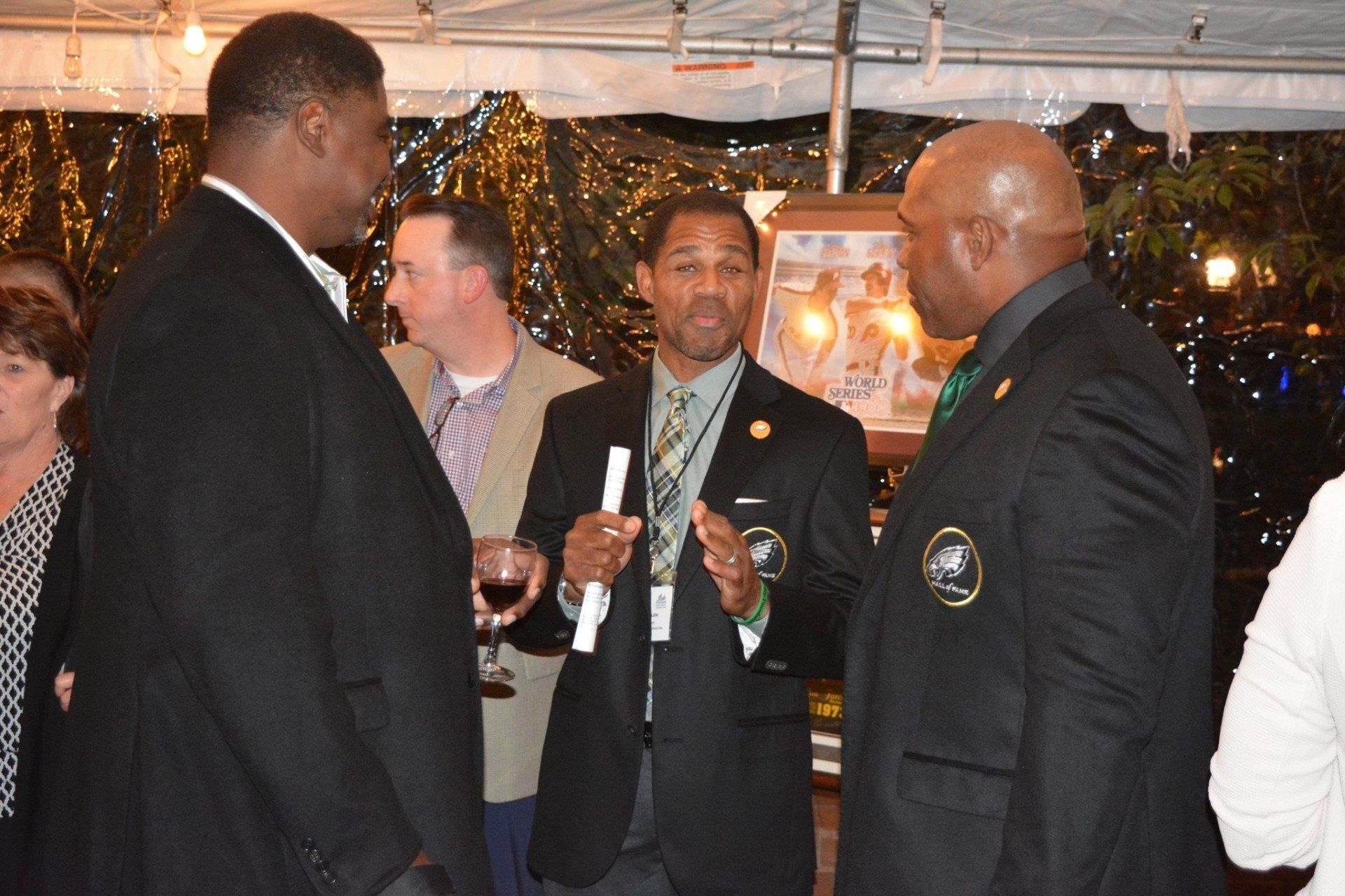 A group of men are standing under a tent talking to each other