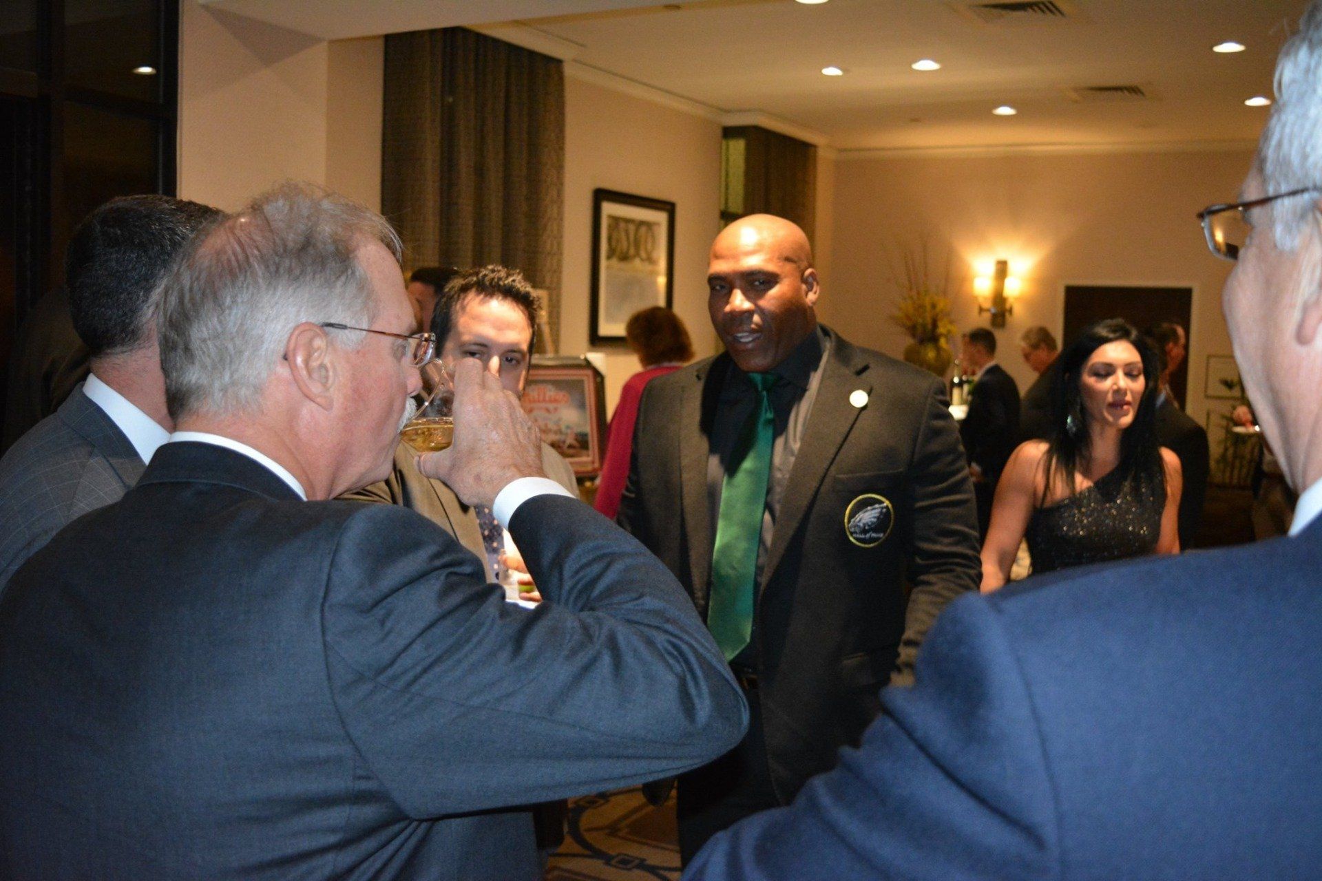 A group of people are standing in a room talking to each other.