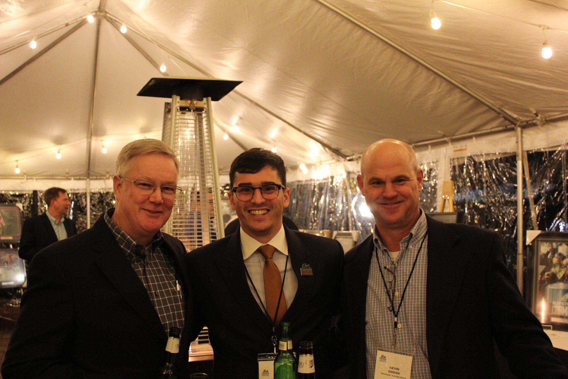 Three men are posing for a picture under a tent.