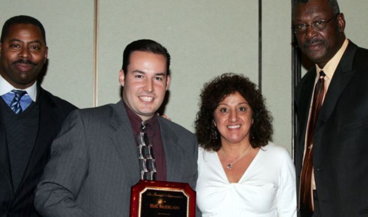 A group of people posing for a picture with a man holding a plaque