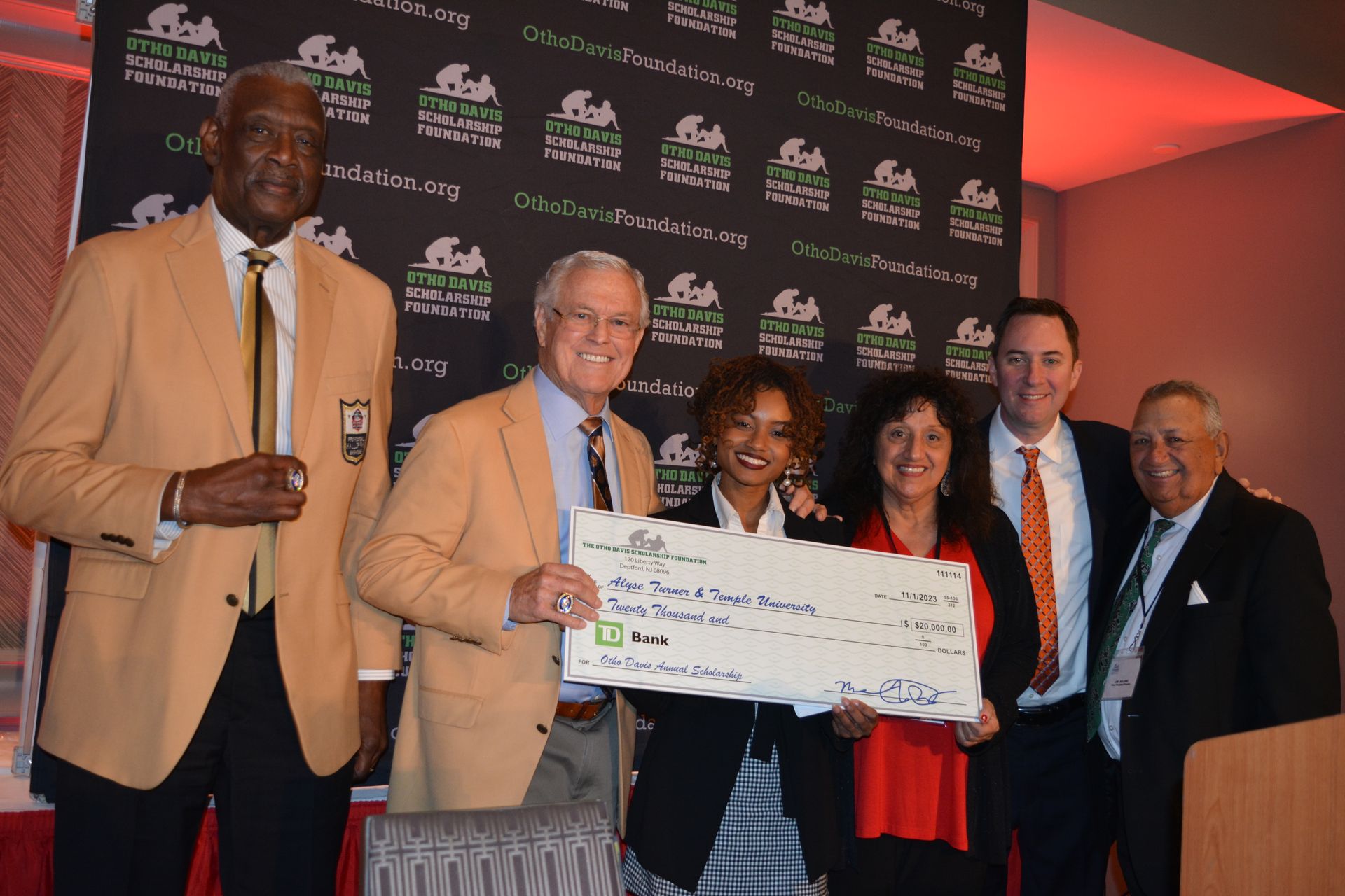 A group of people are posing for a picture while holding a large check.