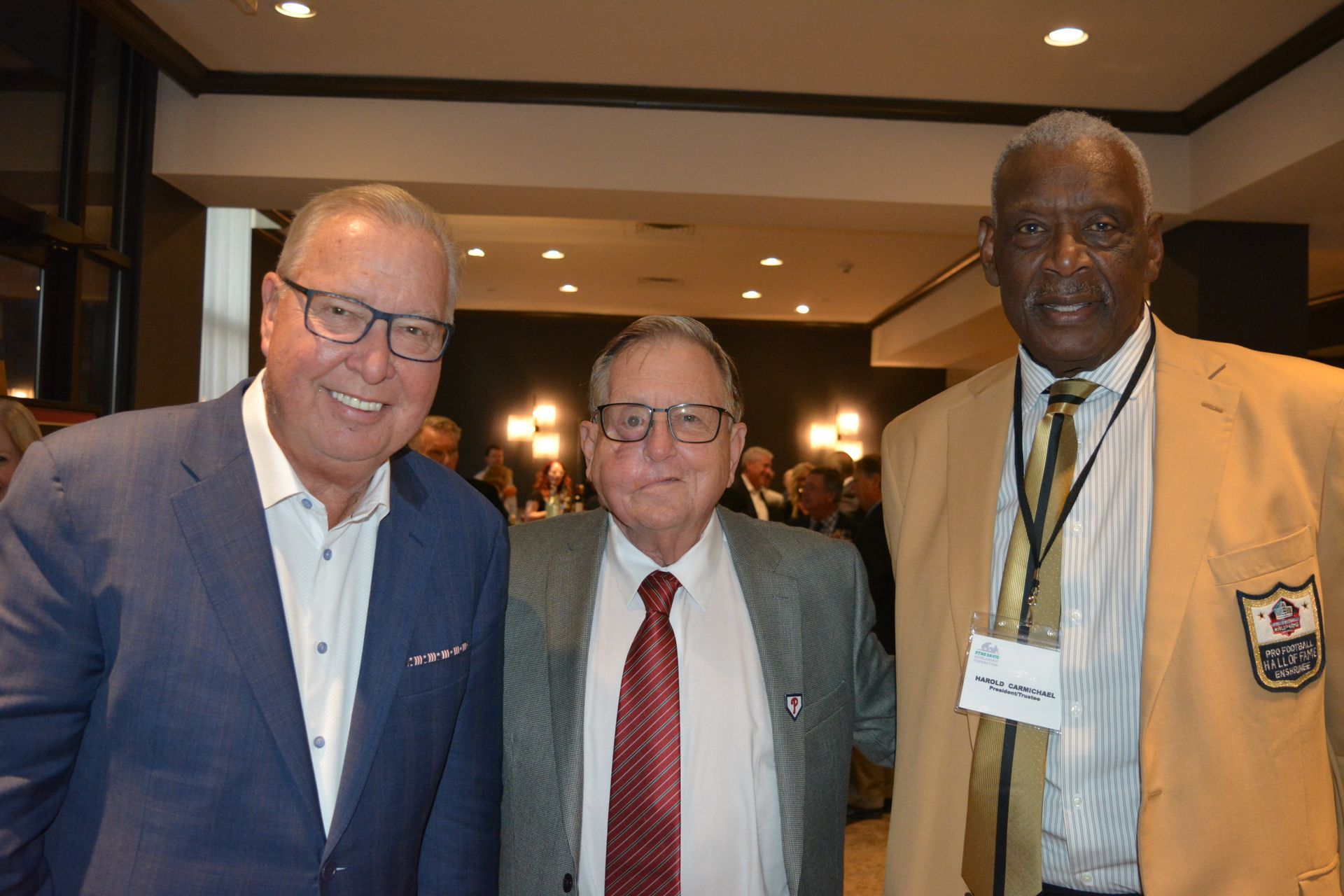 Three men in suits and ties are posing for a picture in a room.