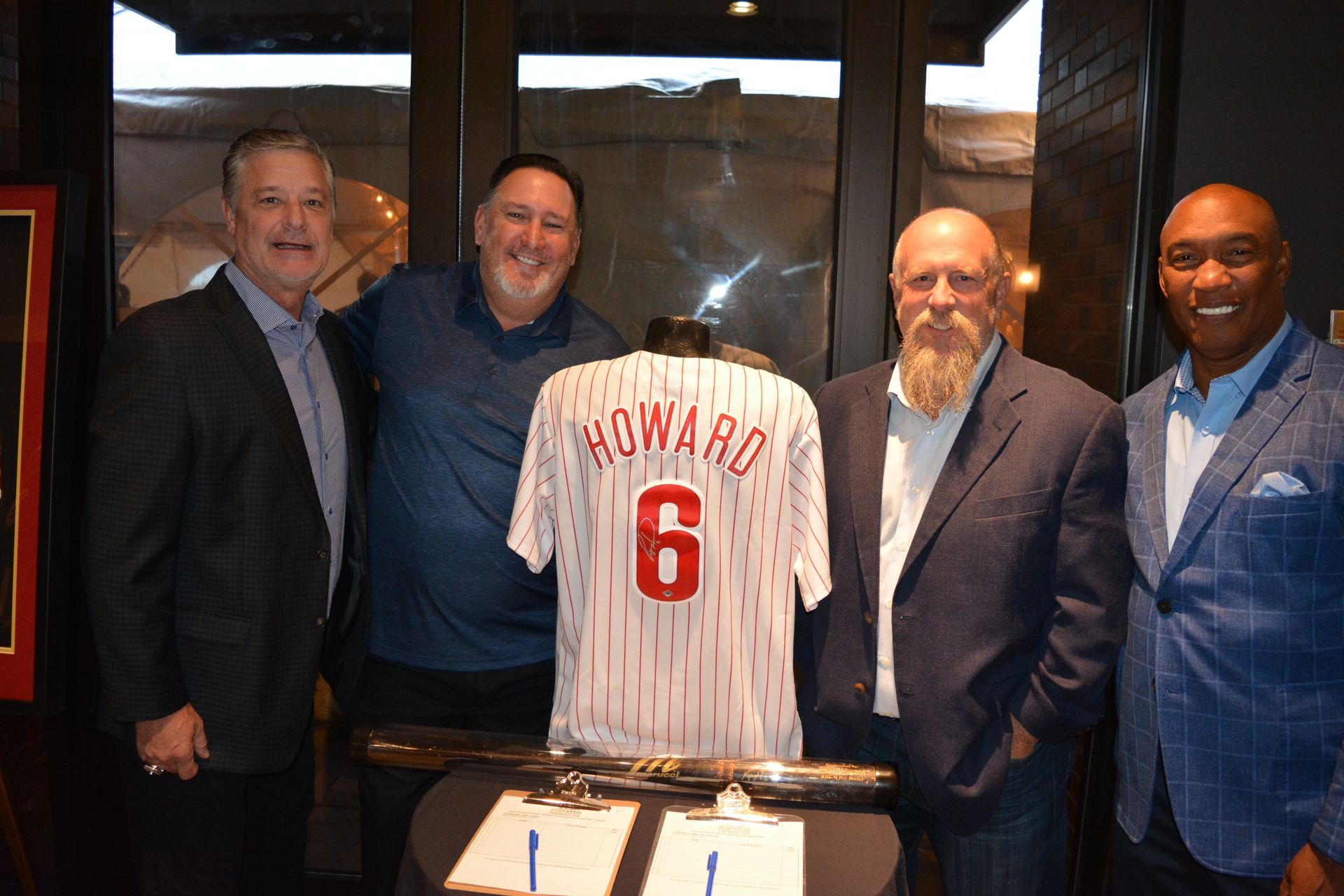 A group of men are standing around a baseball jersey with the number 6 on it.