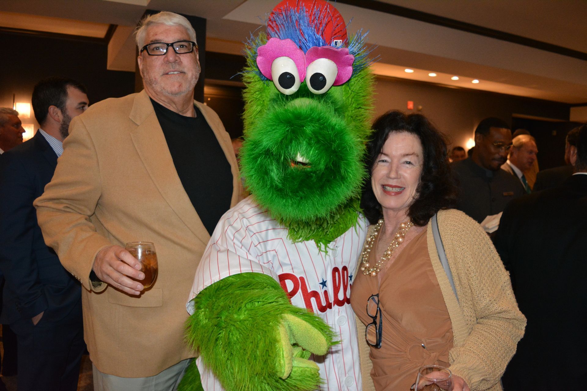 A man and a woman are posing for a picture with a phillies mascot.