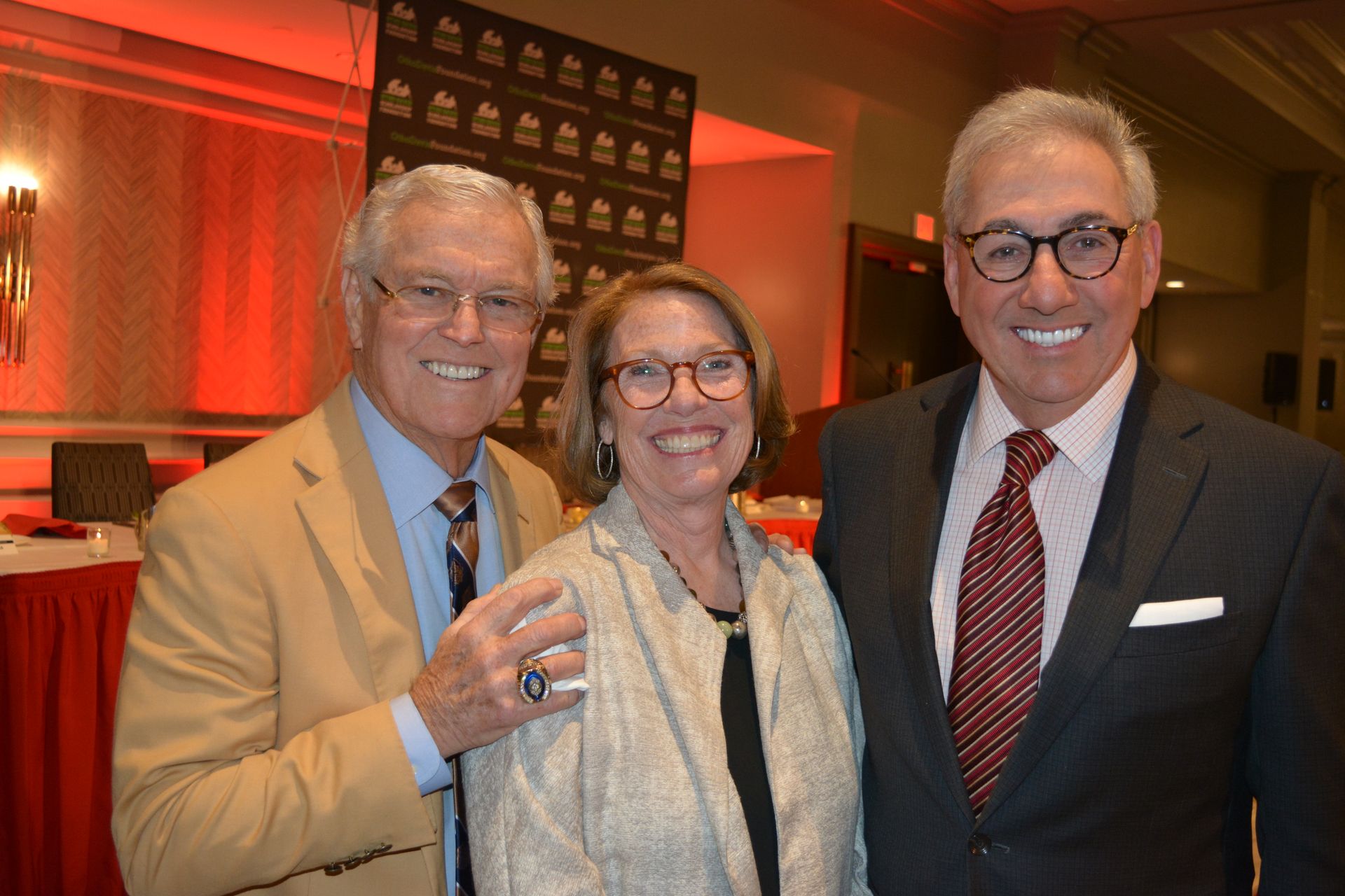 Two men and a woman are posing for a picture in a room.