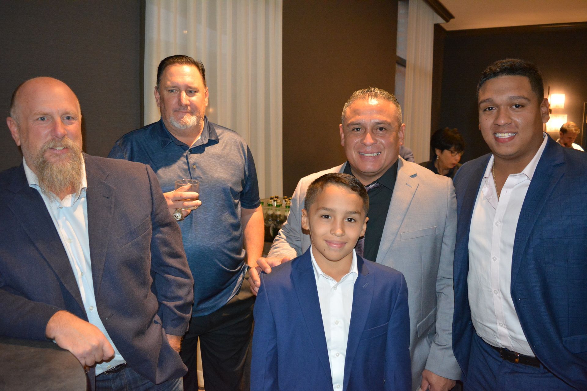 A group of men are posing for a picture with a young boy in a suit.