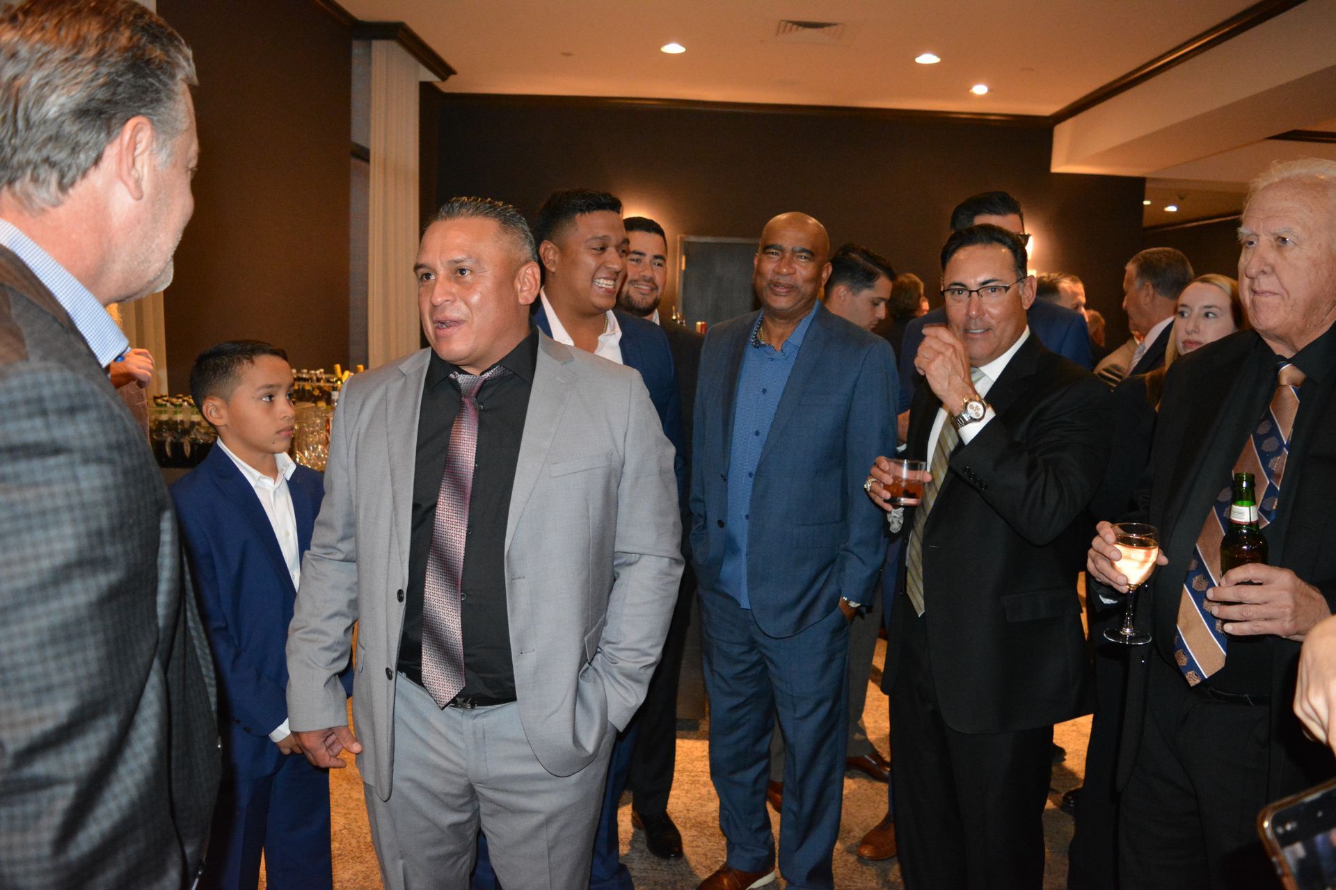 A group of men in suits and ties are standing in a room talking to each other.