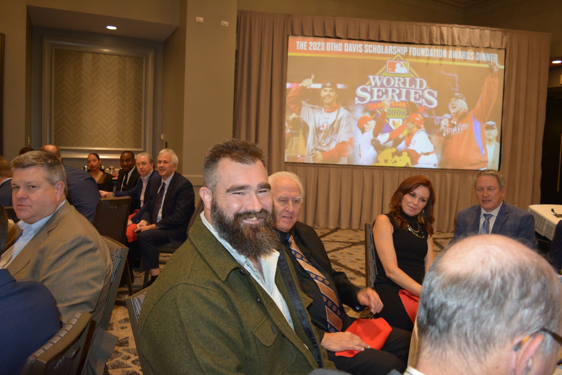 A group of people are sitting in a room in front of a large screen.