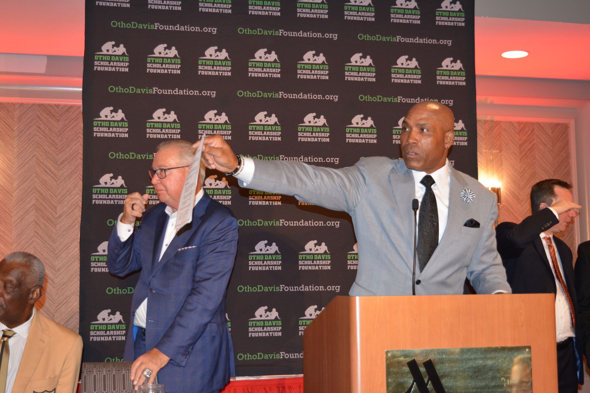 Two men in suits and ties are standing in front of a podium.