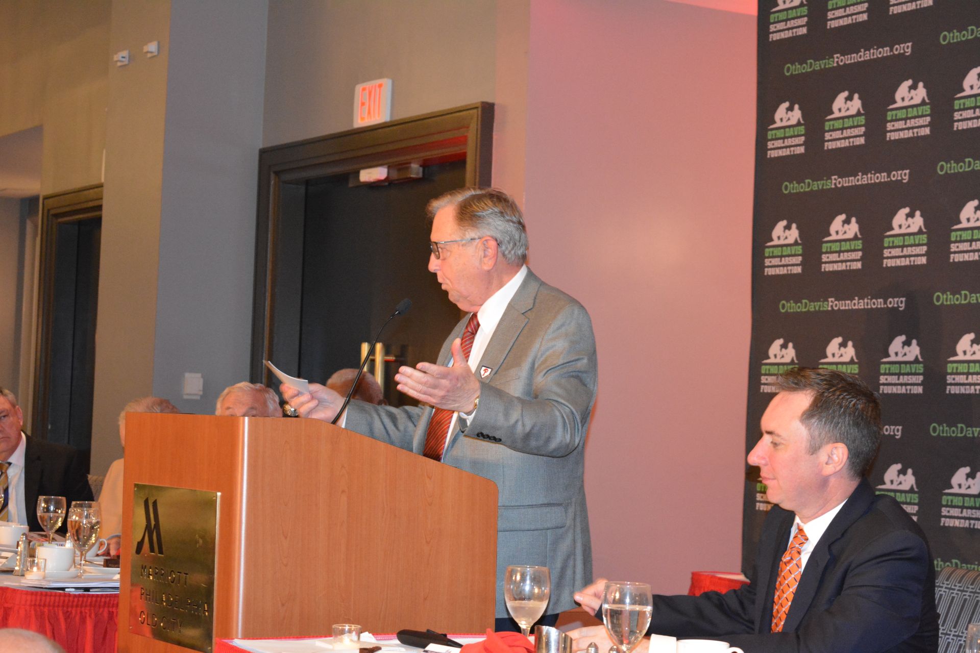 A man in a suit and tie is giving a speech at a podium