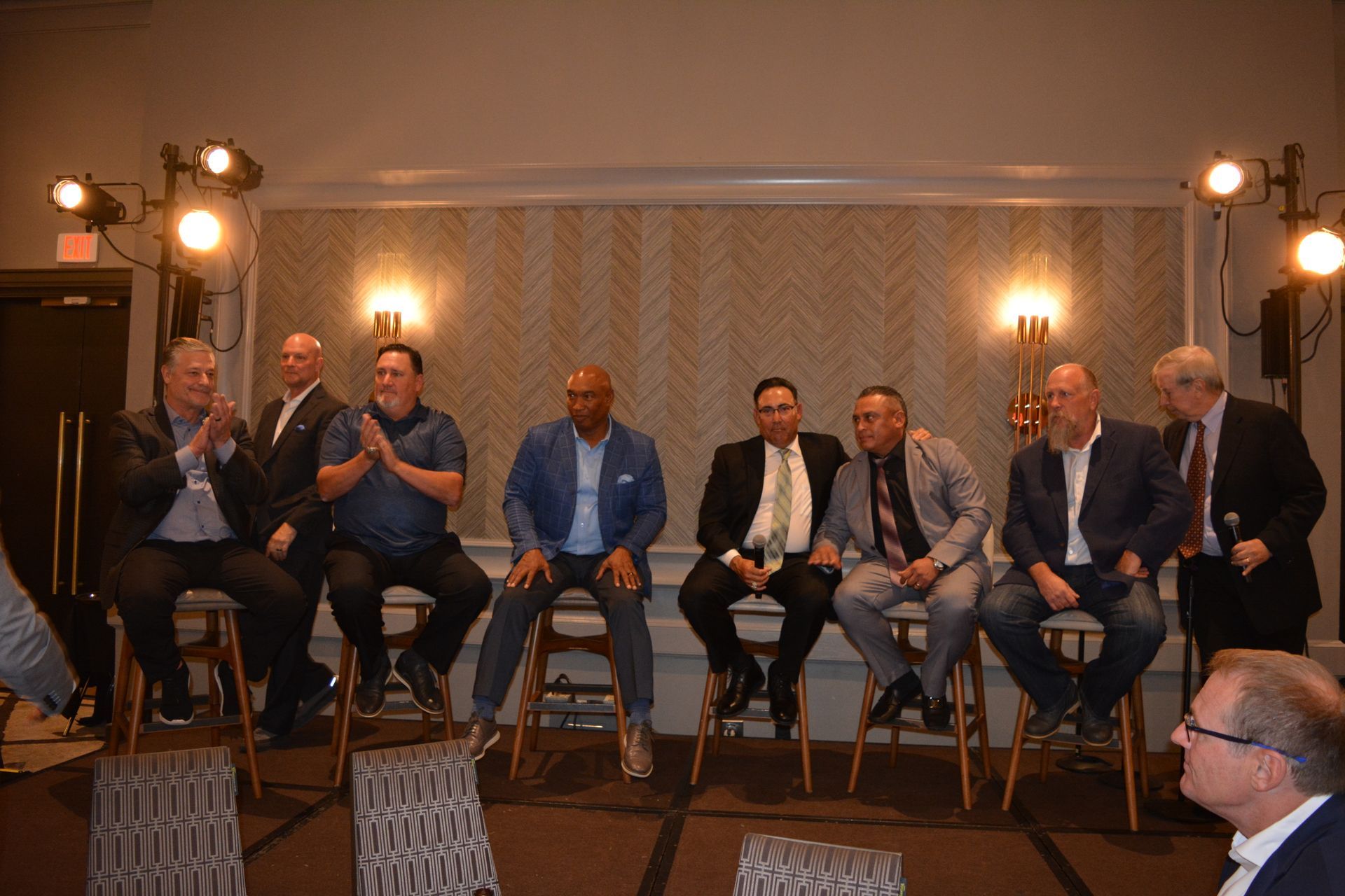 A group of men are sitting on stools in a room.