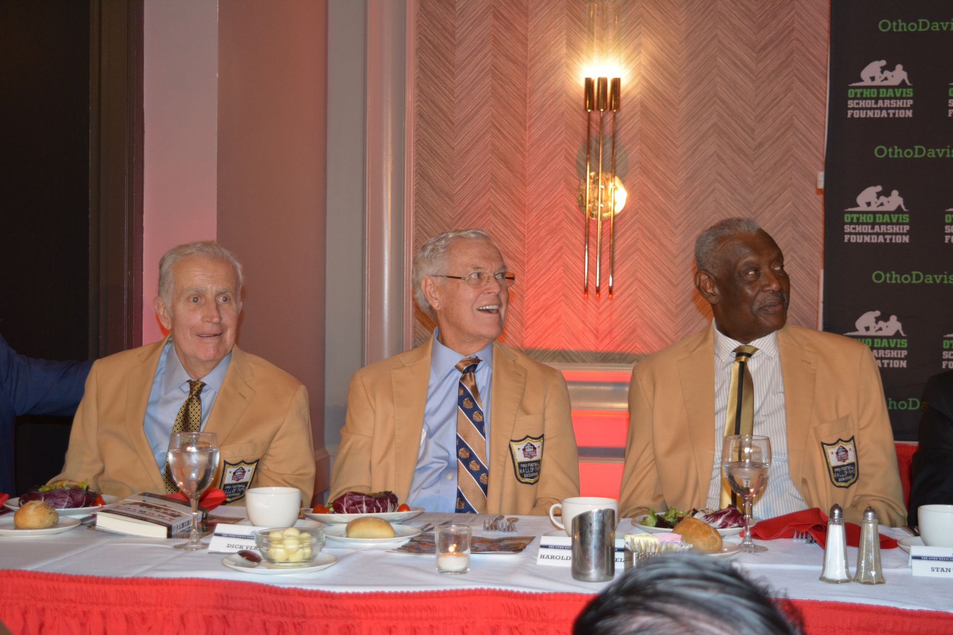 Three men are sitting at a table with plates of food.