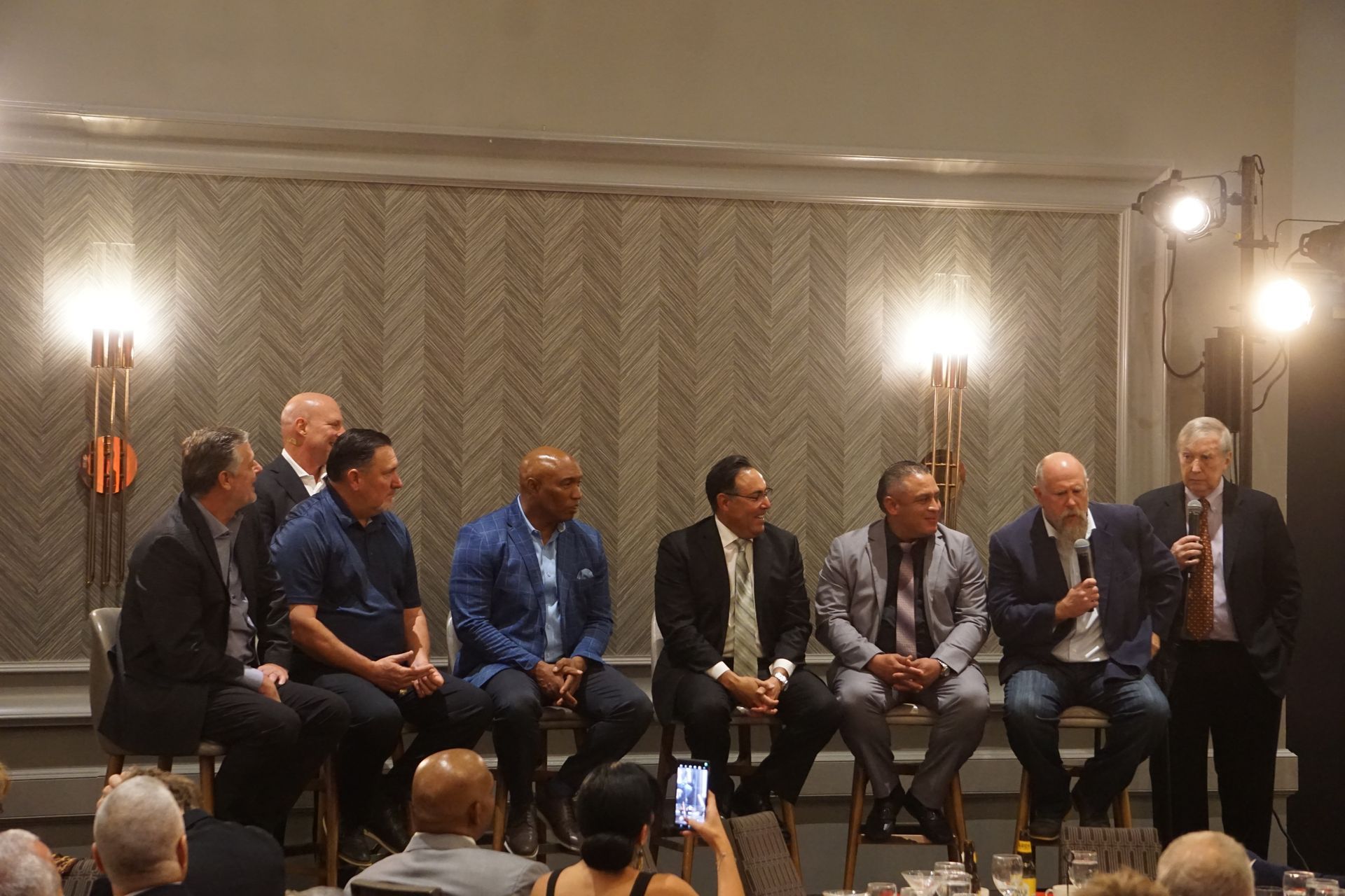 A group of men are sitting in chairs in front of a microphone.