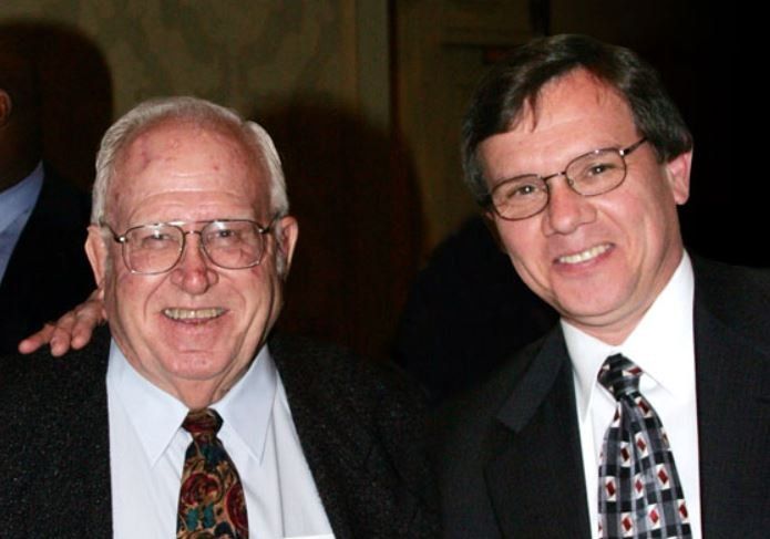 Two men in suits and ties are posing for a picture