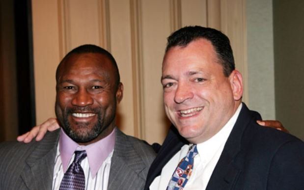 Two men in suits and ties are posing for a picture