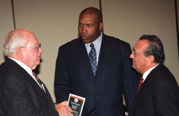 Three men in suits and ties are talking to each other