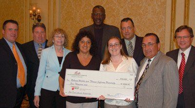 A group of people are posing for a picture while holding a large check.