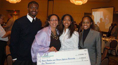 A group of people standing next to each other holding a large check.
