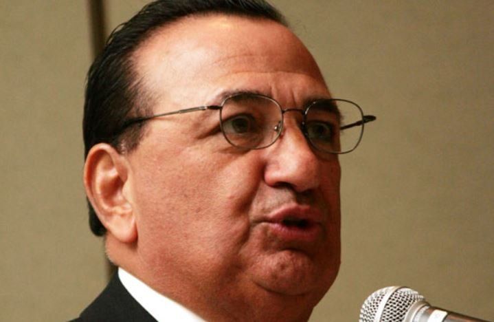 A man wearing glasses is speaking into a microphone