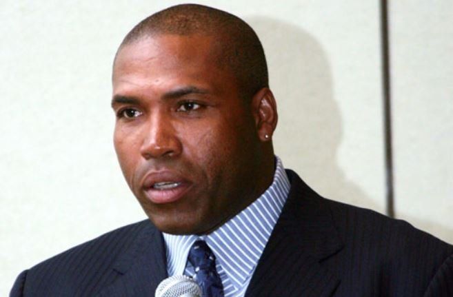 A man in a suit and tie is speaking into a microphone