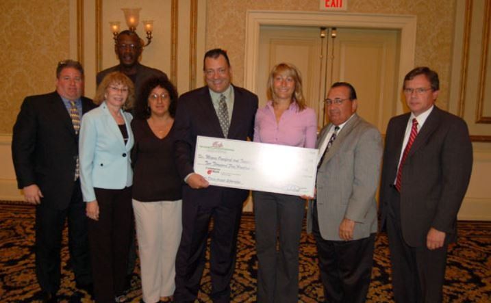 A group of people standing in a room with an exit sign in the background