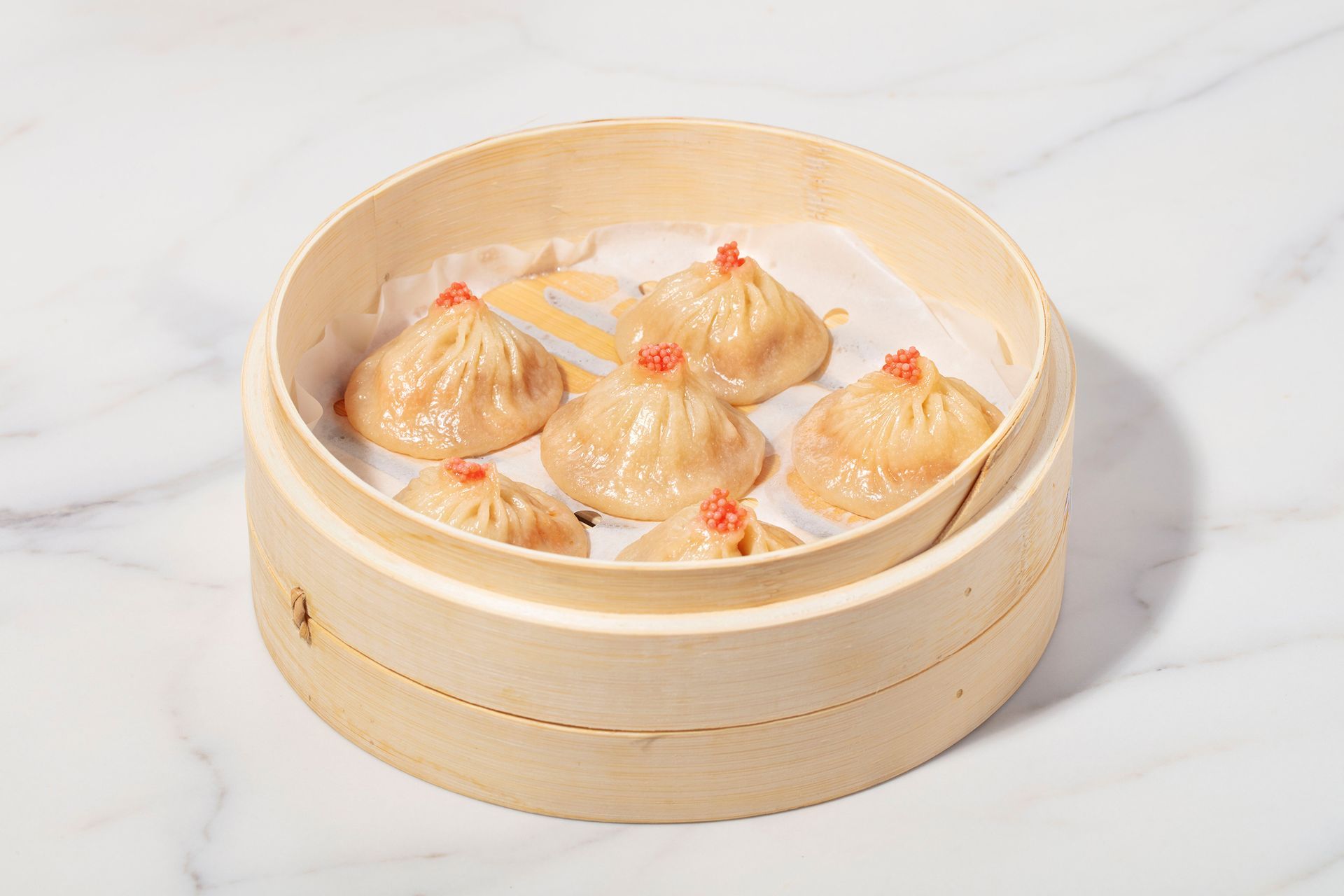 Steamed dumplings in a bamboo basket on a white surface