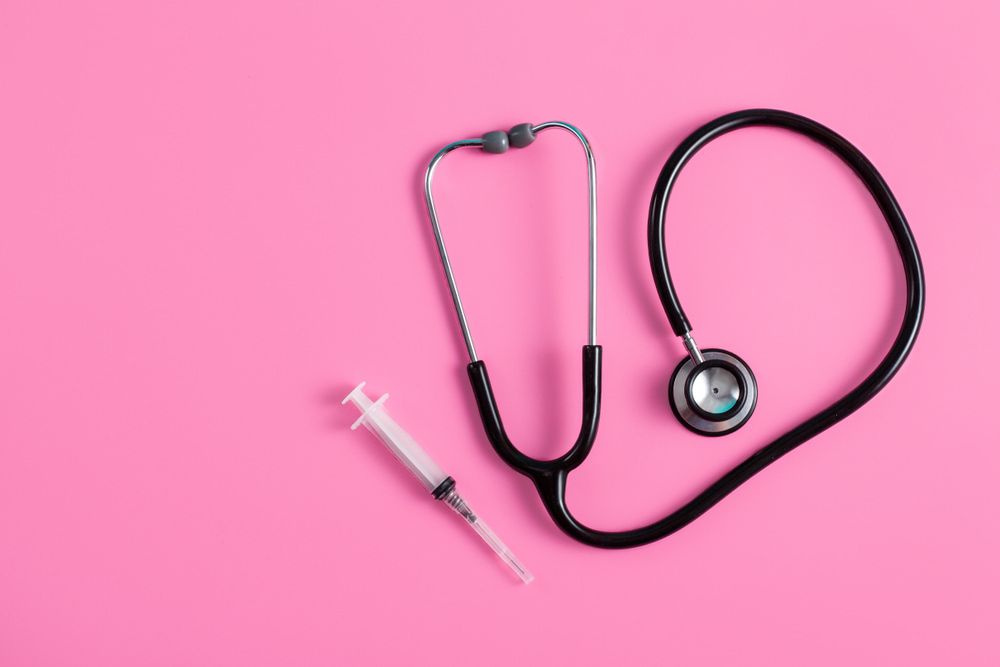 A Stethoscope And Syringe On A Pink Background — Mall Medical Centre In Alice Springs, NT