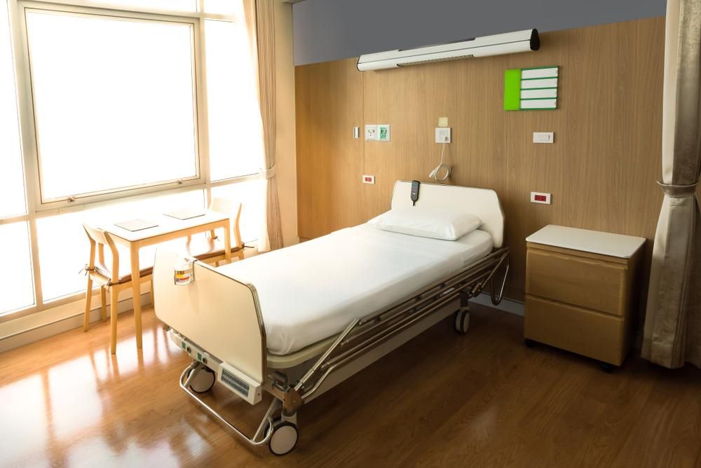 A Hospital Room With A Bed , Nightstand , Table And Chairs — Mall Medical Centre In Alice Springs, NT