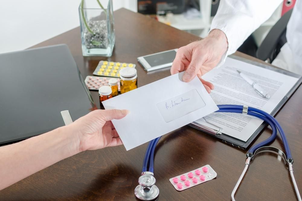 A Doctor Is Handing An Envelope To A Patient — Mall Medical Centre In Alice Springs, NT