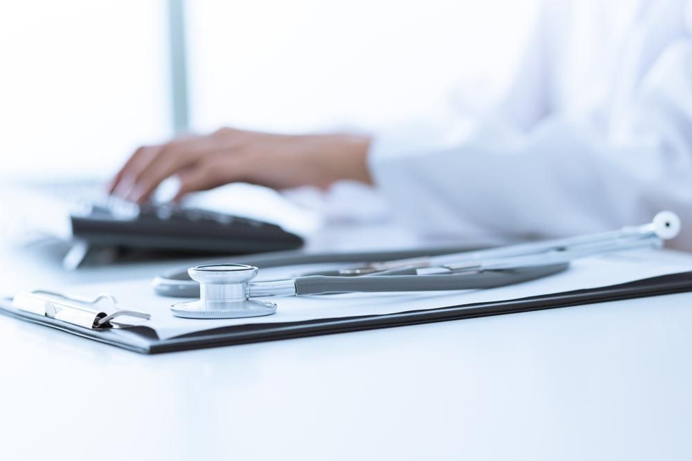A Doctor Is Typing On A Computer And A Stethoscope Sits On A Clipboard — Mall Medical Centre In Alice Springs, NT