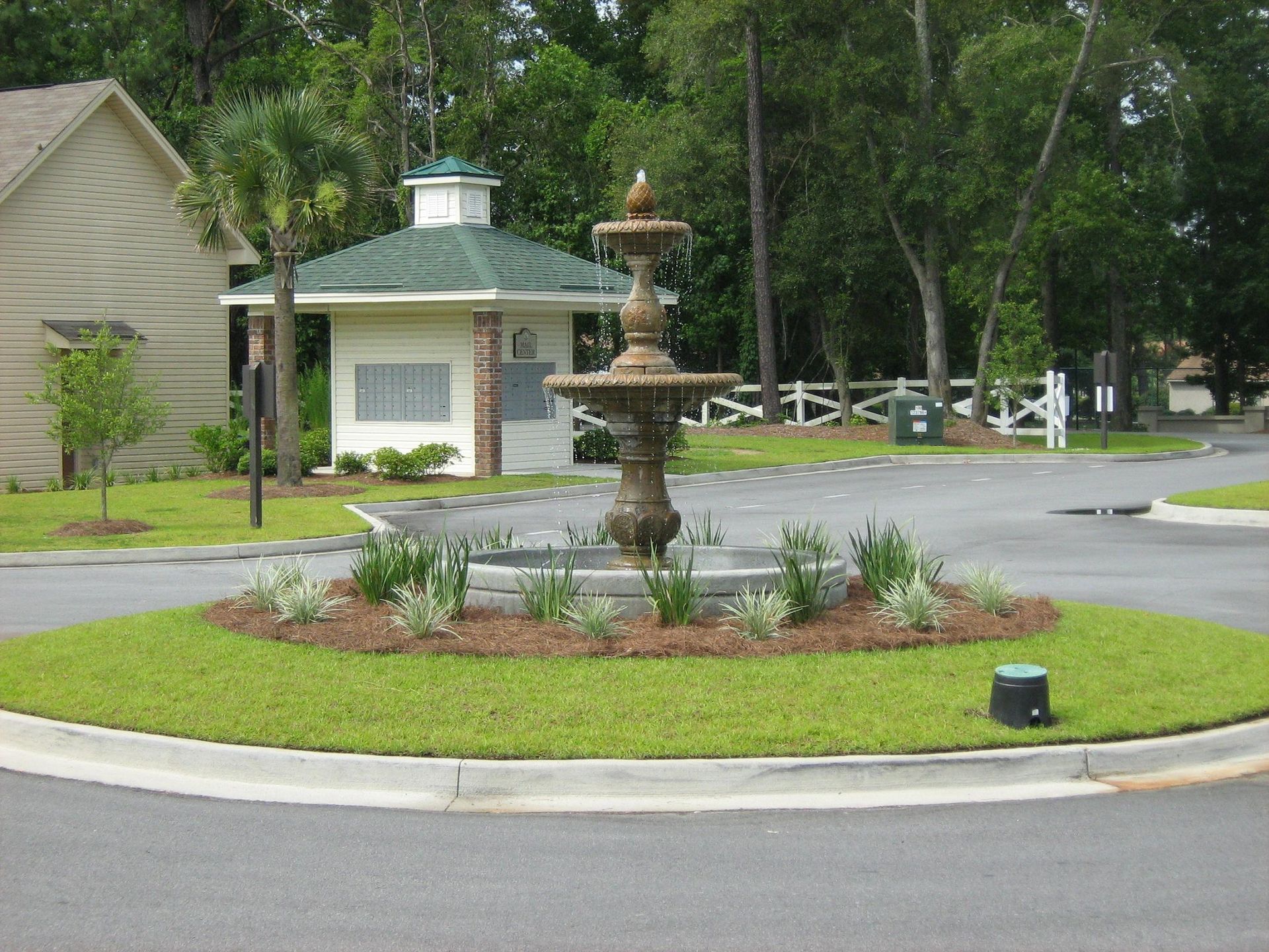 A fountain sits in the middle of a circle of grass