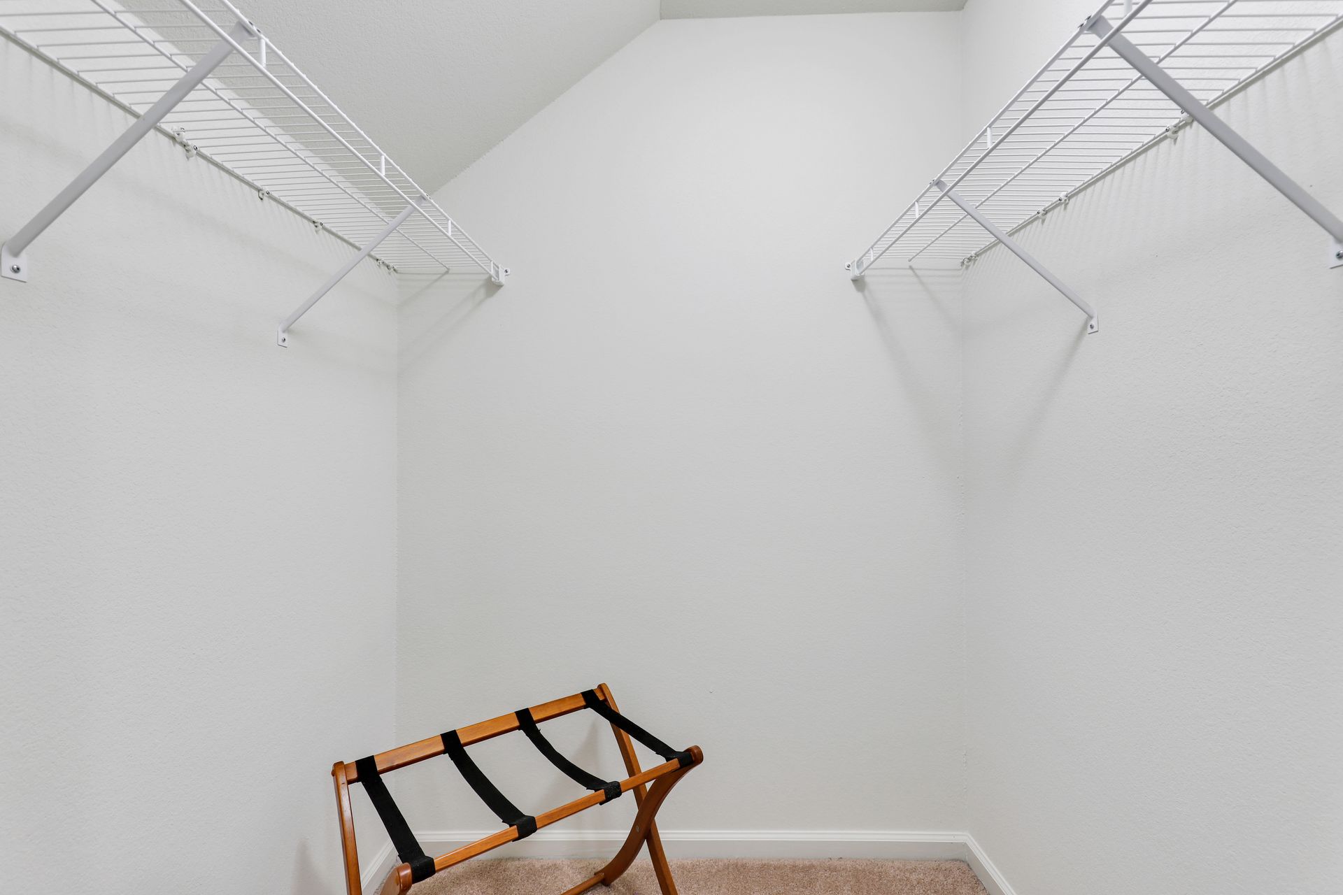 A walk in closet with a folding chair in the corner.