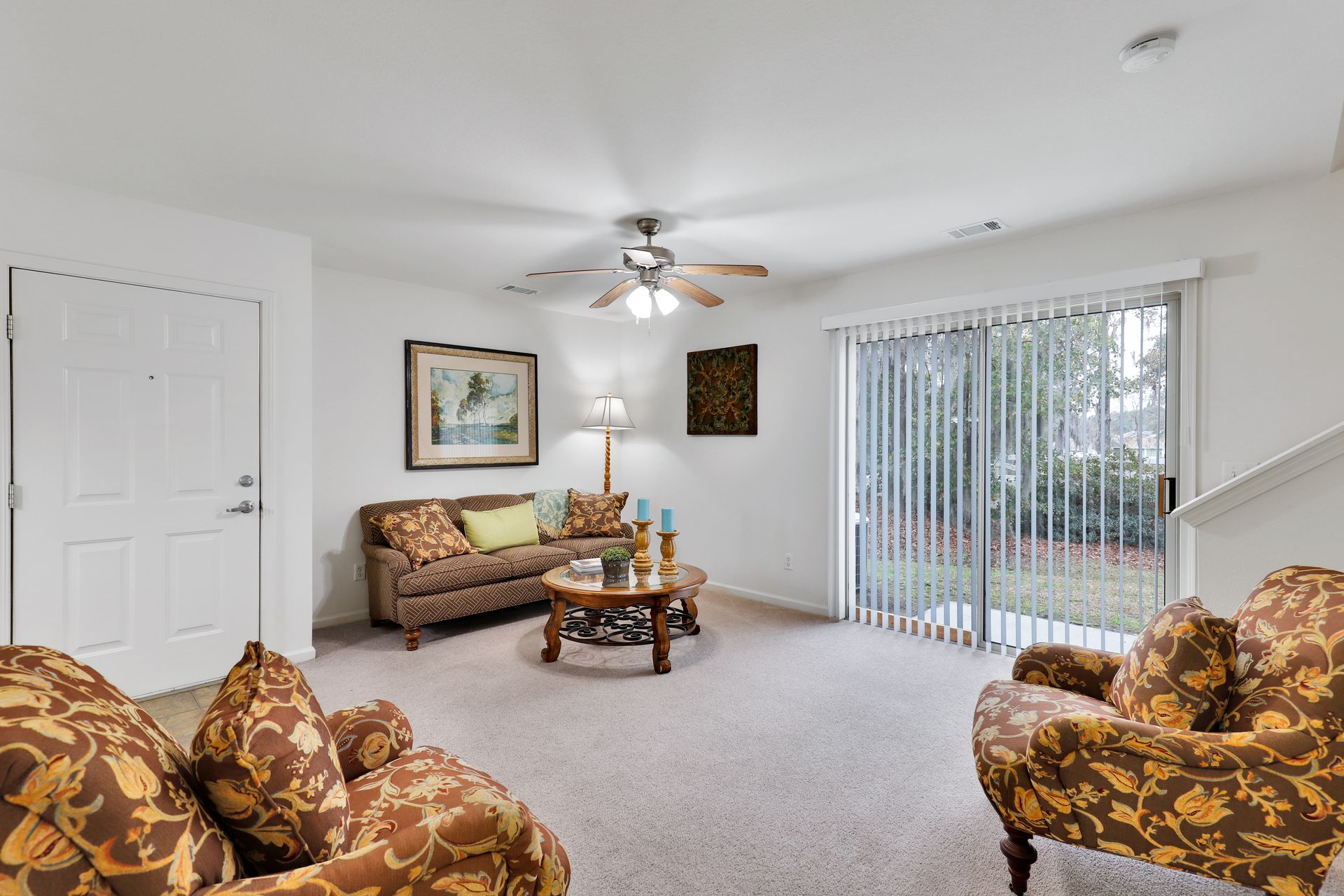 A living room with a couch , chairs , coffee table and sliding glass doors.