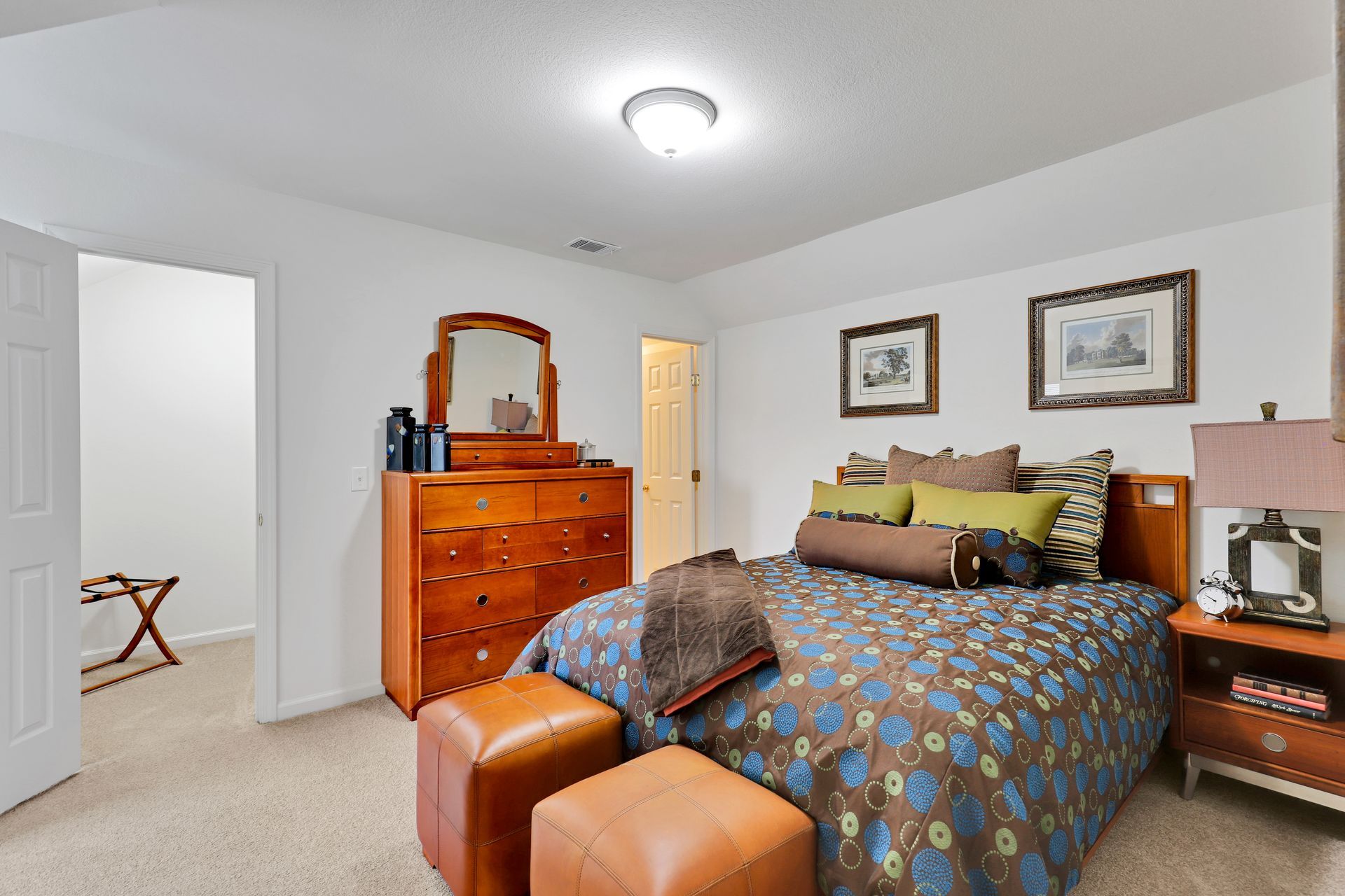 A bedroom with a bed , dresser , nightstand , and mirror.