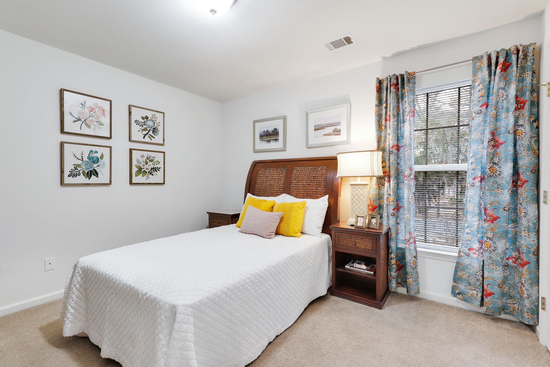 A bedroom with a bed , nightstand , lamp and window.
