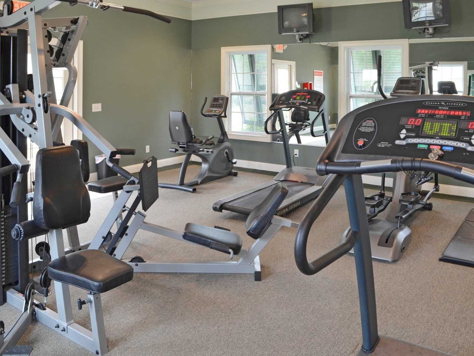 A gym with a treadmill and a rowing machine