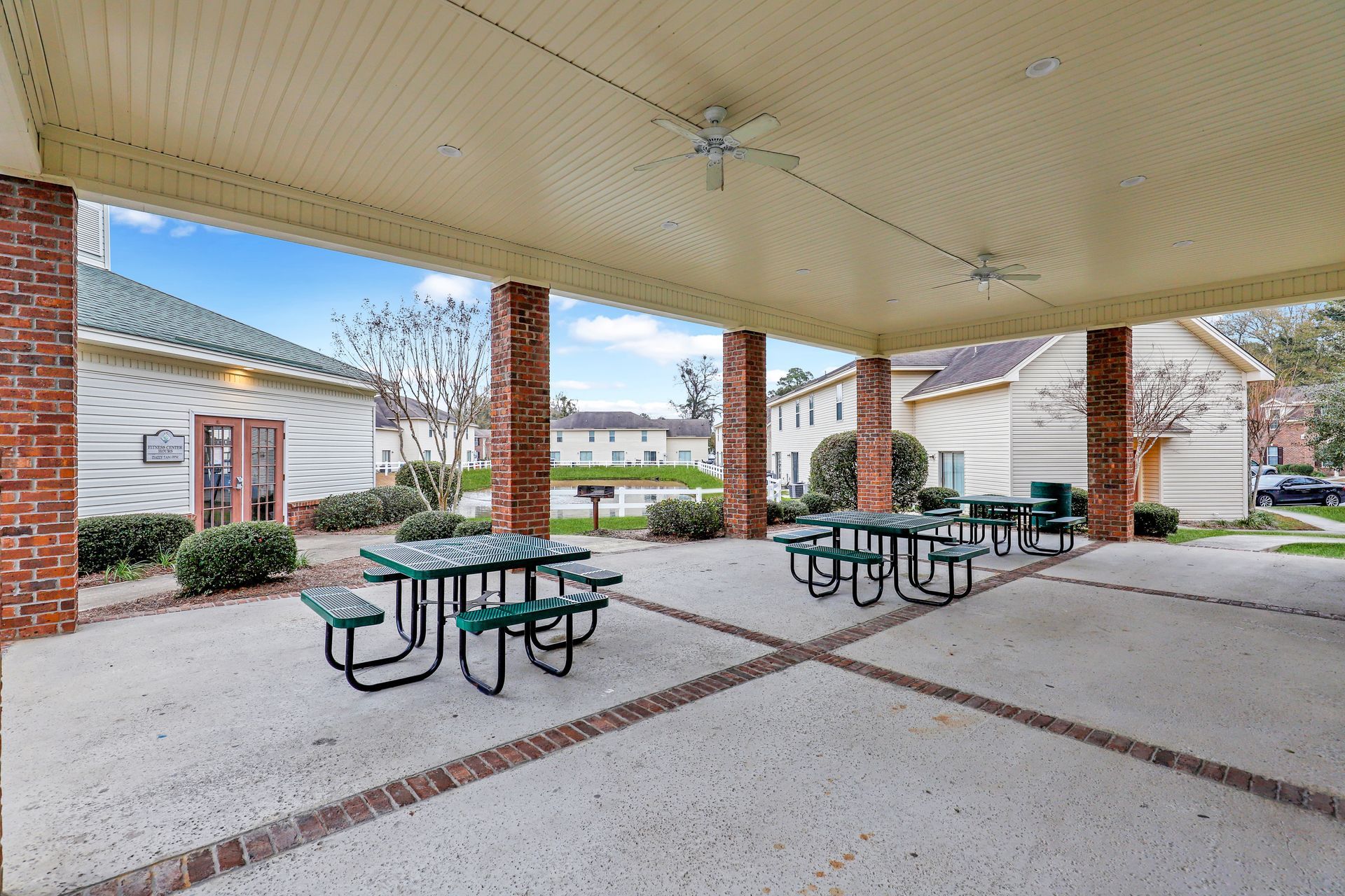 A group of picnic tables under a covered patio with a ceiling fan.