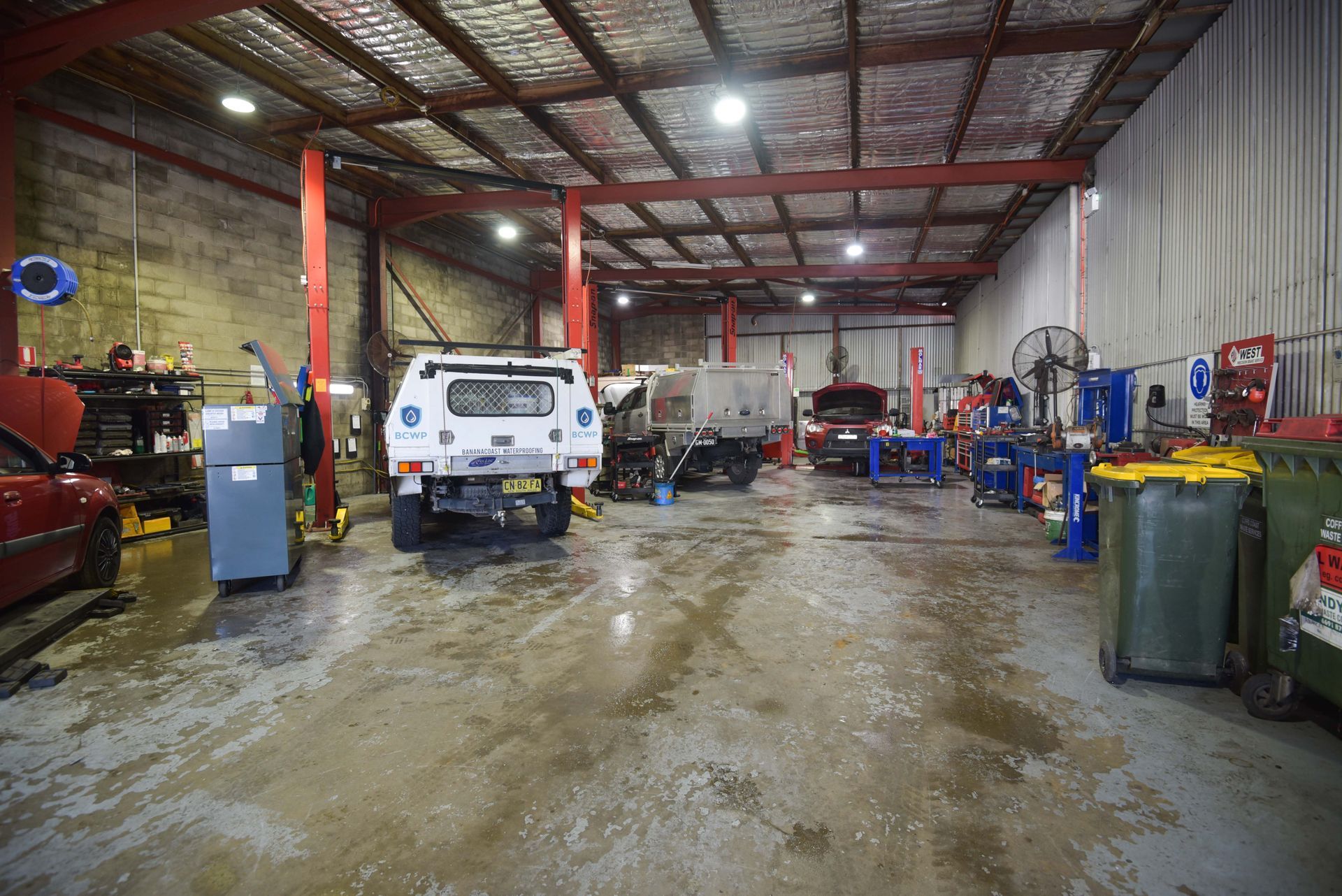 The inside of a garage with 3 cars parked while getting repaired — Advanced Automotive Services in Coffs Harbour, NSW
