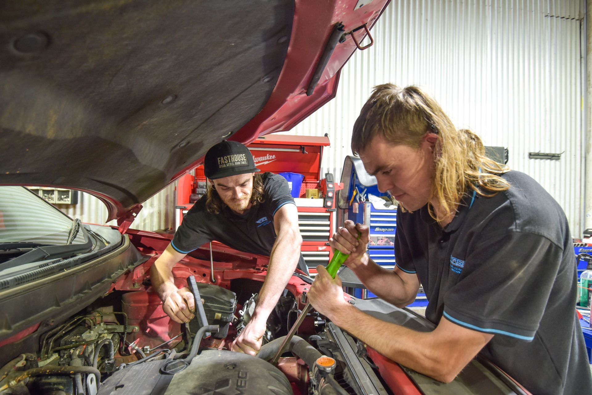 Two guys are working on the inside of a car bonnet in garage — Advanced Automotive Services in Coffs Harbour, NSW