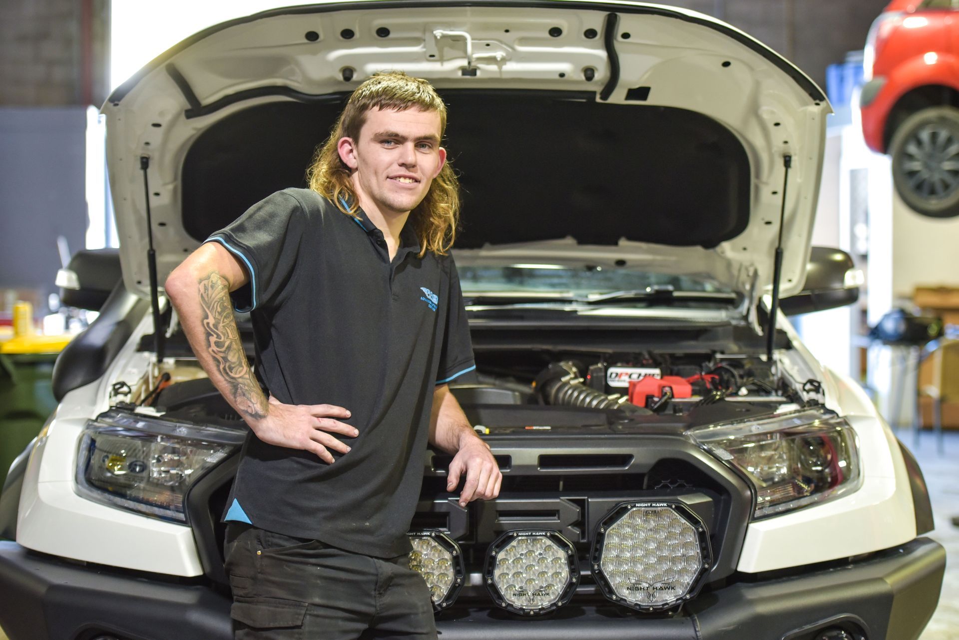 A man is leaning on the front of a car — Advanced Automotive Services in Coffs Harbour, NSW