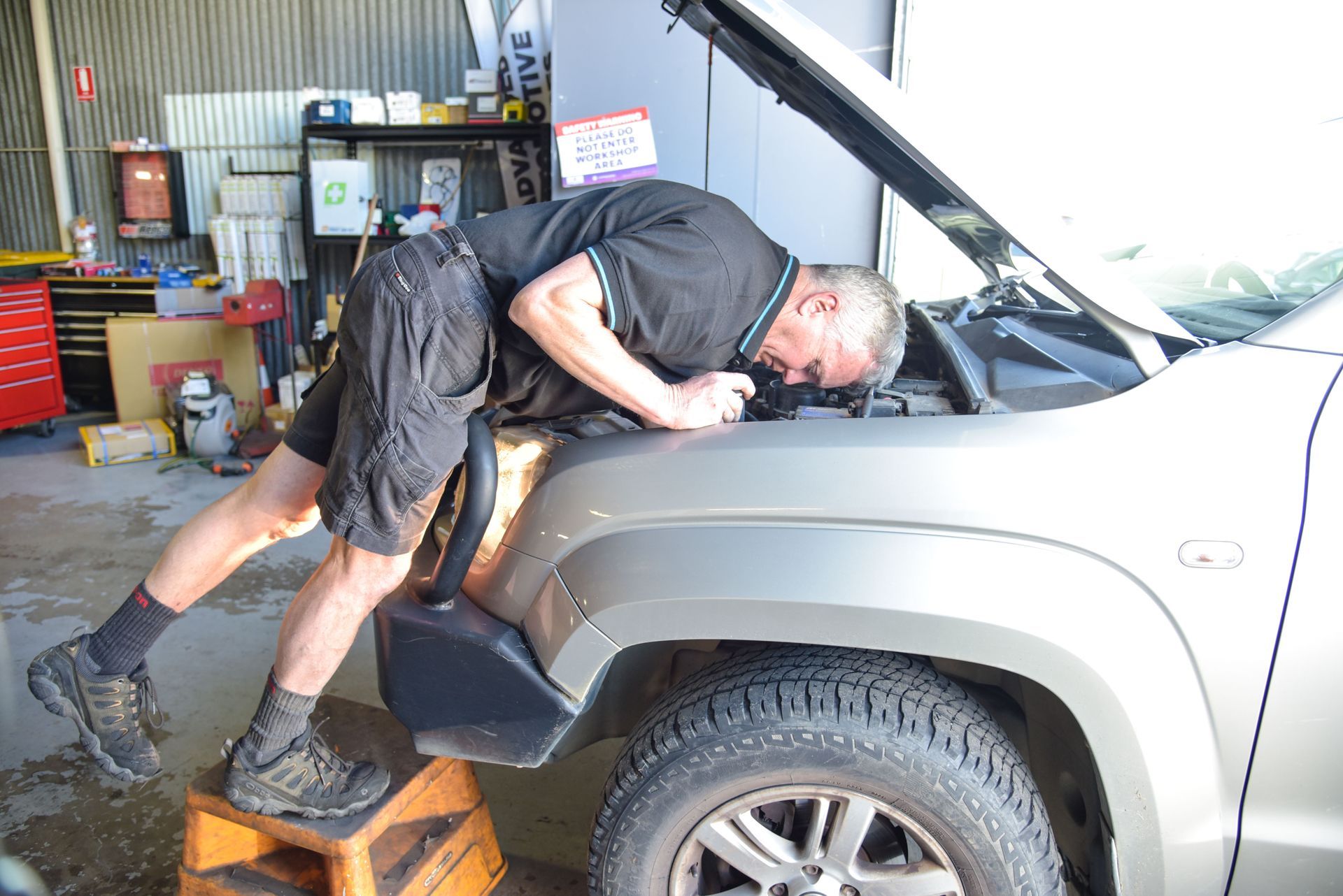 A man is looking at the inside of a car bonnet — Advanced Automotive Services in Coffs Harbour, NSW