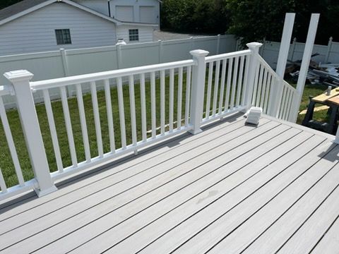 A newly built deck with white railing, light gray composite decking, and a set of stairs.