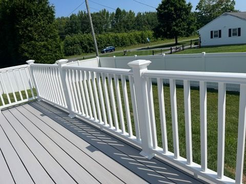 Gray painted wooden deck with a sliding glass door and the side of a house.
